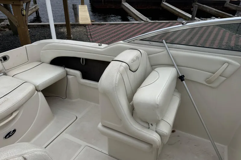 Slide: The Image of 2004 Sea Ray 215 Weekender boat interior with white seating and dock view. - 11