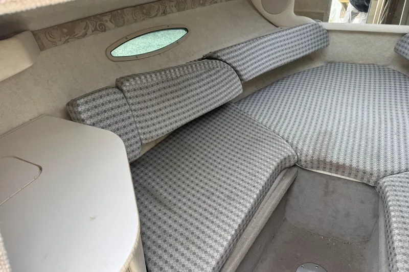Slide: The Image of 2004 Sea Ray 215 Weekender cabin interior with patterned cushions and compact table. - 13