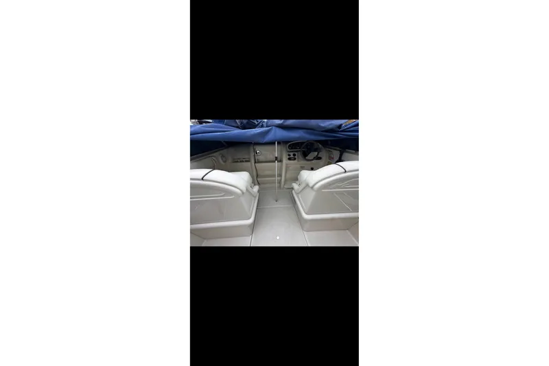 Slide: The Image of 2004 Sea Ray 215 Weekender boat interior with white seating and covered dashboard. - 5