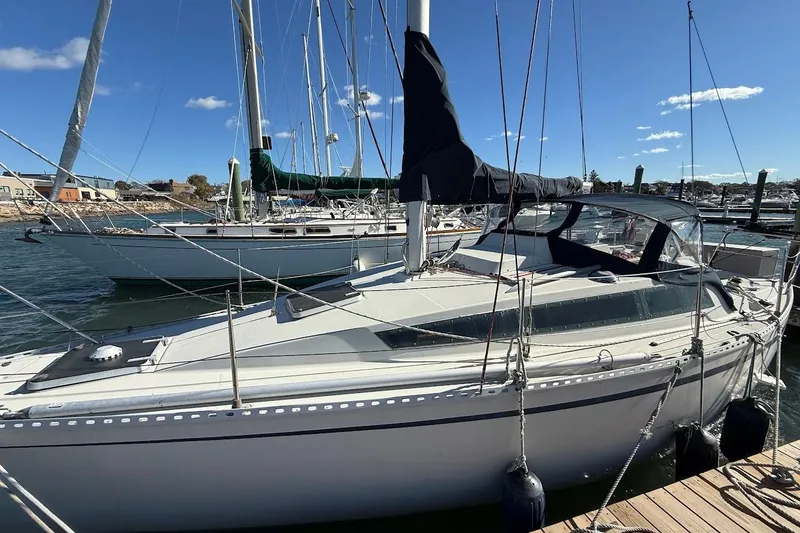 The Image of 1985 Jouet 950 sailboat docked at marina under clear blue sky. - 1