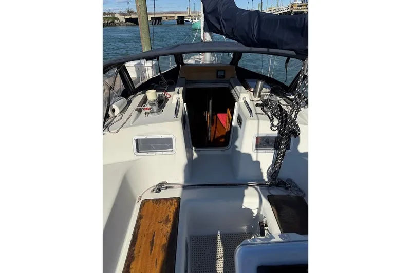 Slide: The Image of 1985 Jouet 950 sailboat cockpit with ropes and equipment, docked by the water. - 4