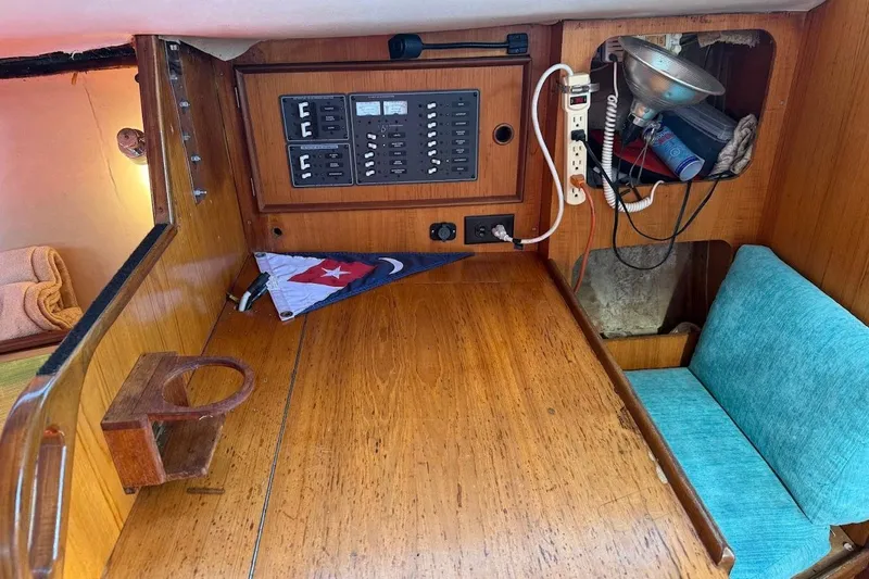 Slide: The Image of 1985 Jouet 950 sailboat interior with control panel, wooden table, and turquoise seating. - 9