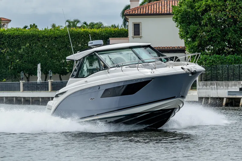 The Image of 2023 Sea Ray Sundancer 320 Outboard cruising on water near luxury waterfront homes. - 0