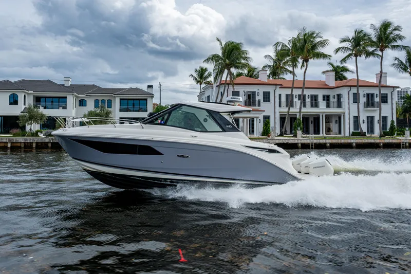 Slide: The Image of 2023 Sea Ray Sundancer 320 Outboard cruising near luxury waterfront homes. - 10