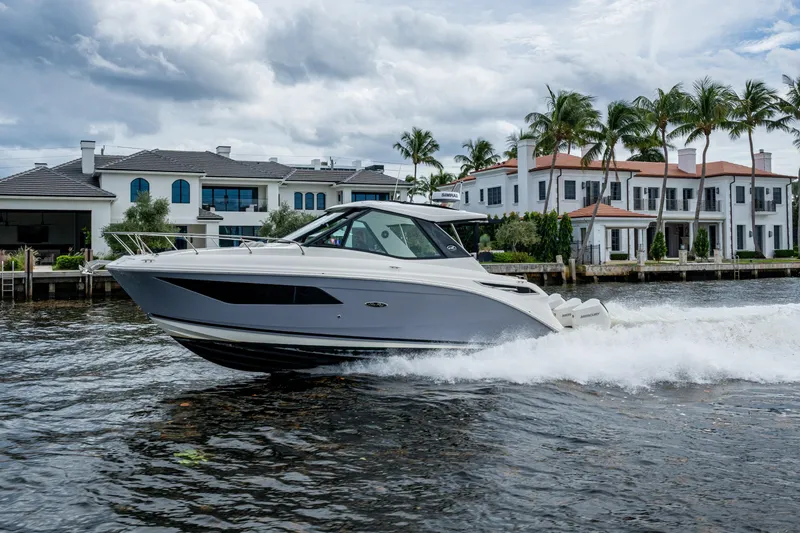 Slide: The Image of 2023 Sea Ray Sundancer 320 Outboard cruising near luxury waterfront homes. - 11