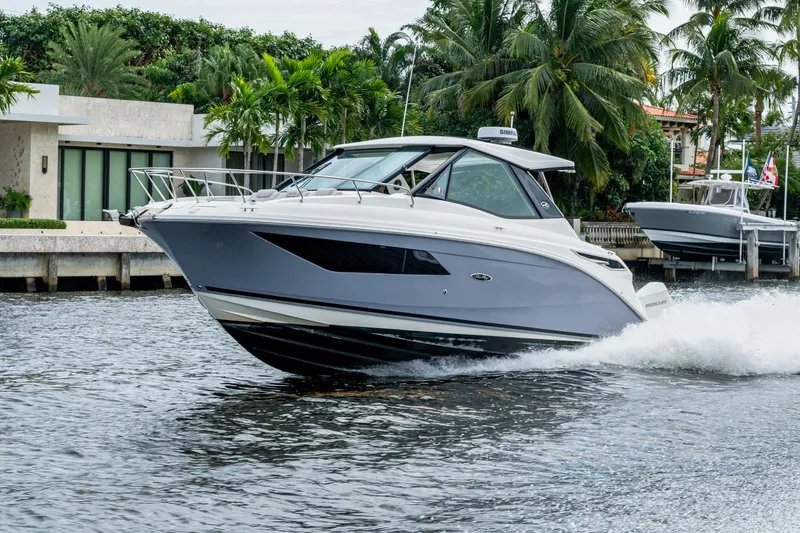 Slide: The Image of 2023 Sea Ray Sundancer 320 Outboard cruising on a scenic waterway with lush greenery. - 13