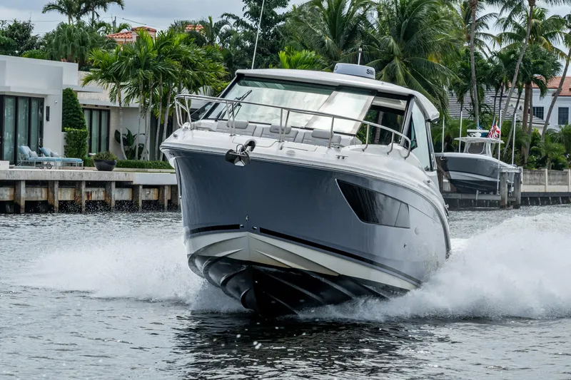 Slide: The Image of 2023 Sea Ray Sundancer 320 Outboard cruising on a scenic waterway with palm trees. - 14