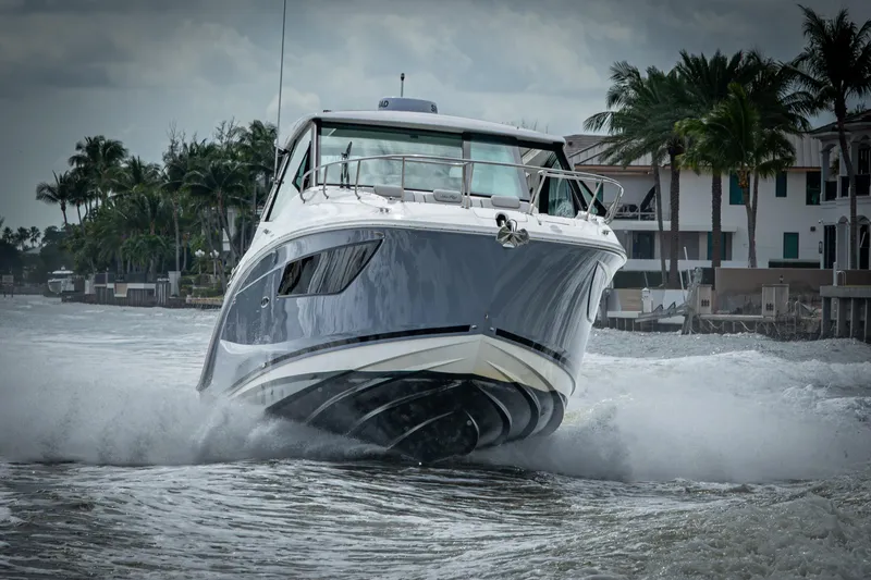 Slide: The Image of 2023 Sea Ray Sundancer 320 Outboard cruising on water near palm trees and waterfront homes. - 18
