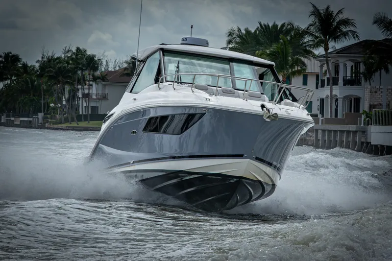 Slide: The Image of 2023 Sea Ray Sundancer 320 Outboard cruising on a waterway near luxury homes. - 19