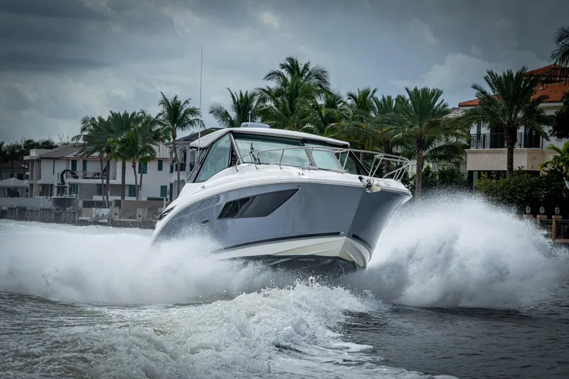 Slide: The Image of 2023 Sea Ray Sundancer 320 Outboard cruising on water with palm trees in background. - 20