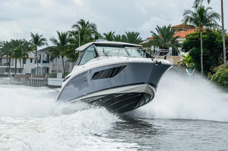 Slide: The Image of 2023 Sea Ray Sundancer 320 Outboard cruising on water with palm trees in background. - 21