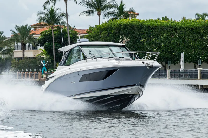 Slide: The Image of 2023 Sea Ray Sundancer 320 Outboard cruising on water near palm trees. - 22
