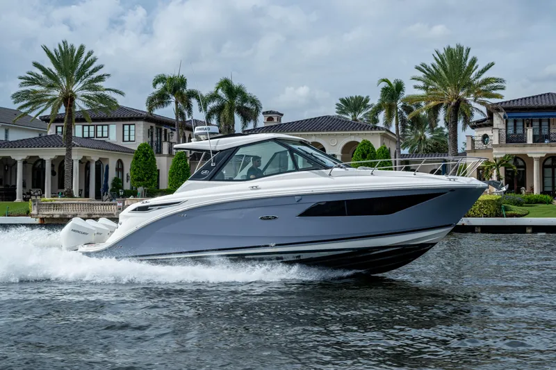 Slide: The Image of 2023 Sea Ray Sundancer 320 Outboard cruising on water near luxury waterfront homes. - 25