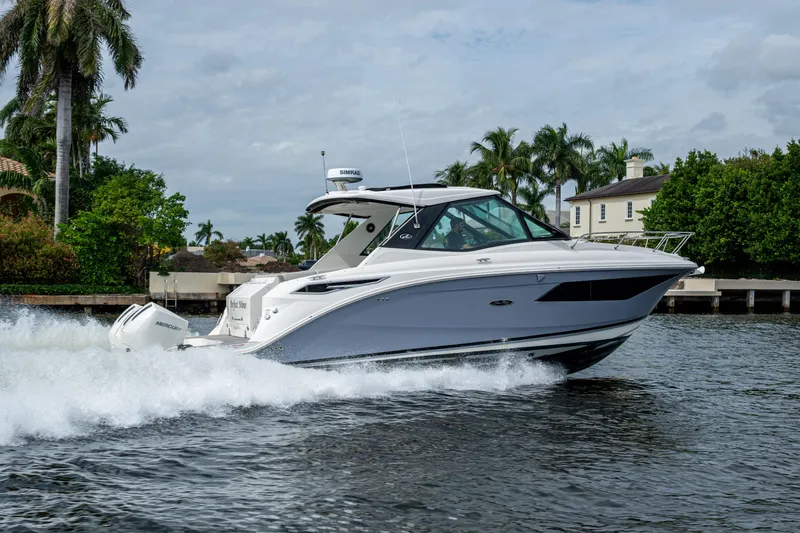 Slide: The Image of 2023 Sea Ray Sundancer 320 Outboard cruising on a scenic waterway with palm trees. - 27