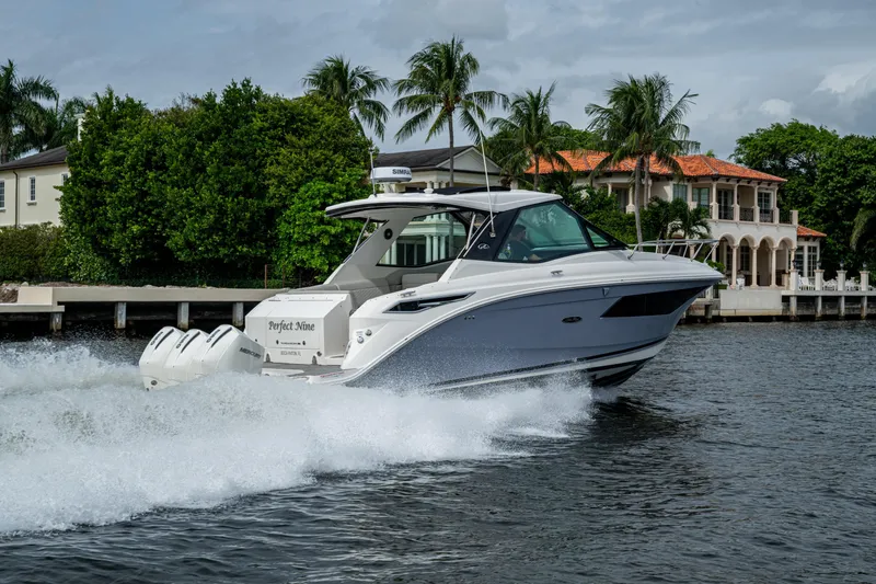 Slide: The Image of 2023 Sea Ray Sundancer 320 Outboard cruising on a scenic waterway with luxury homes. - 28
