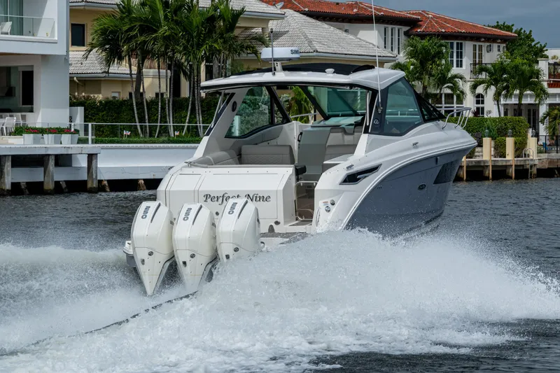 Slide: The Image of 2023 Sea Ray Sundancer 320 Outboard cruising on water near luxury homes. - 30