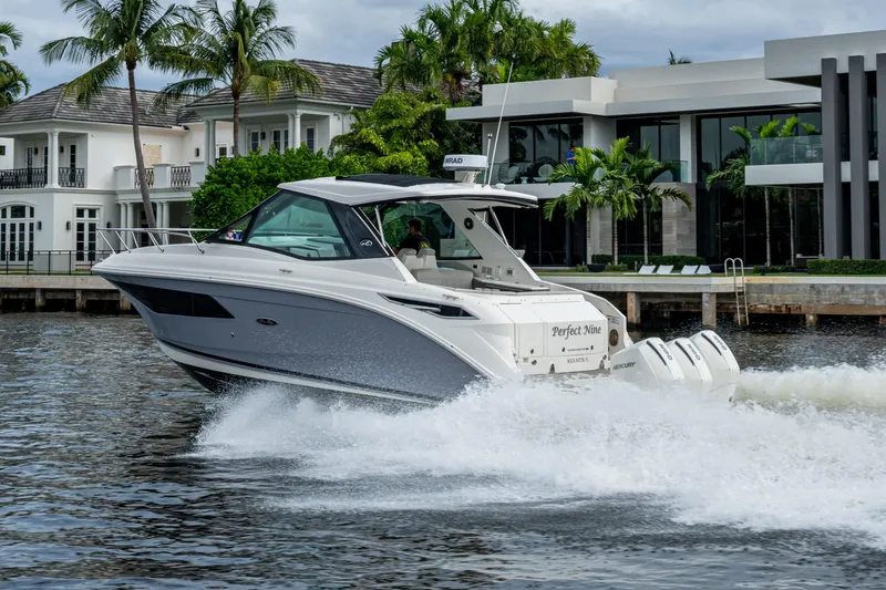 Slide: The Image of 2023 Sea Ray Sundancer 320 Outboard cruising near luxury waterfront homes. - 4