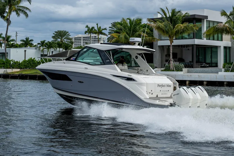 Slide: The Image of 2023 Sea Ray Sundancer 320 Outboard cruising on water near modern waterfront homes. - 5