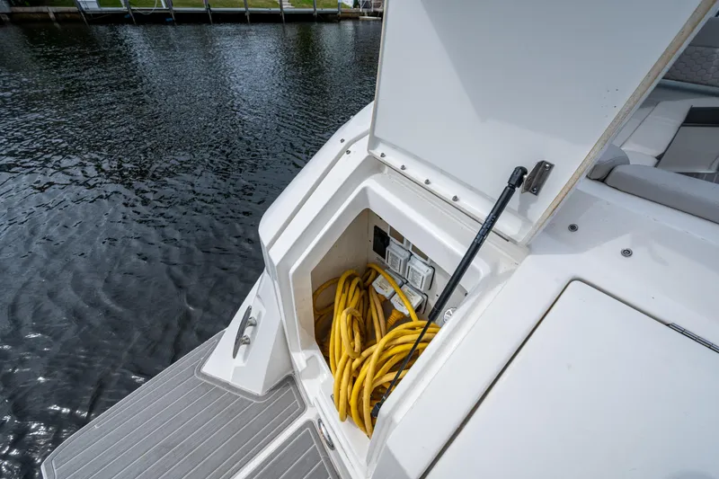 Slide: The Image of 2023 Sea Ray Sundancer 320 Outboard storage compartment with yellow cables by the water. - 53