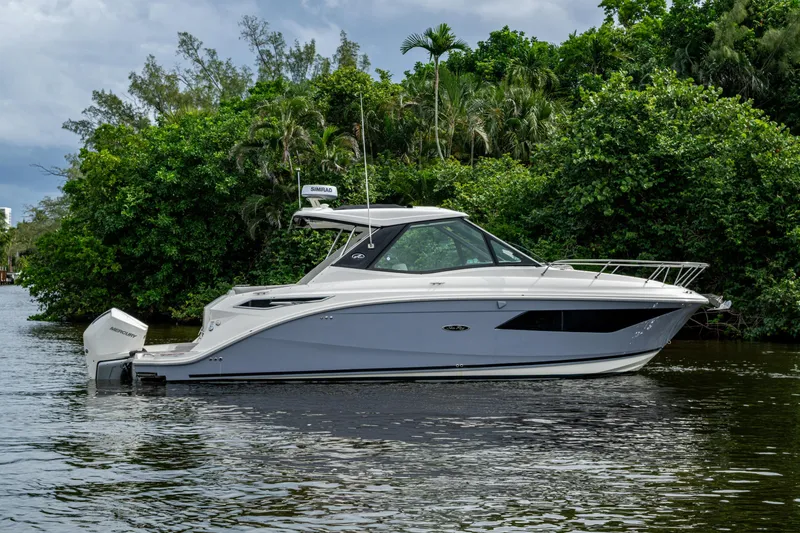 Slide: The Image of 2023 Sea Ray Sundancer 320 Outboard boat on calm water, surrounded by lush greenery. - 61