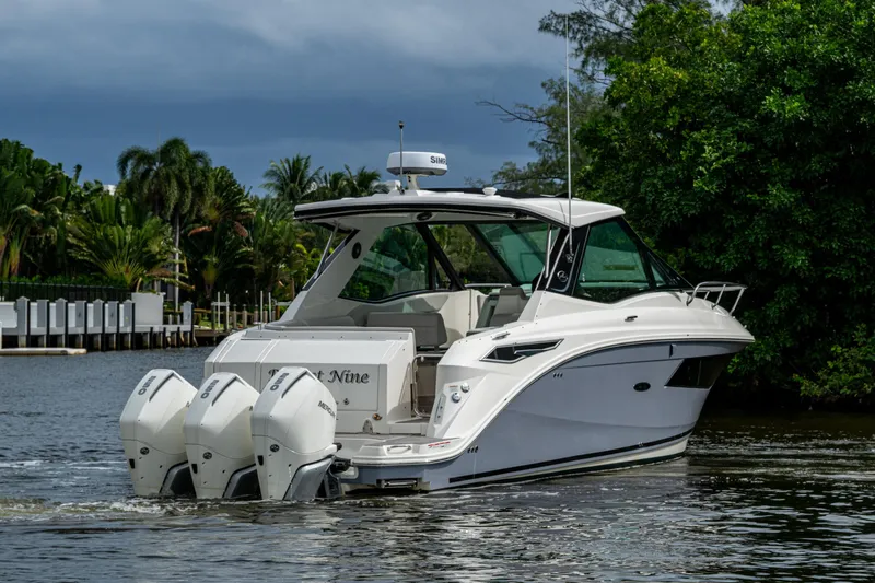 Slide: The Image of 2023 Sea Ray Sundancer 320 Outboard cruising on a scenic waterway with lush greenery. - 63