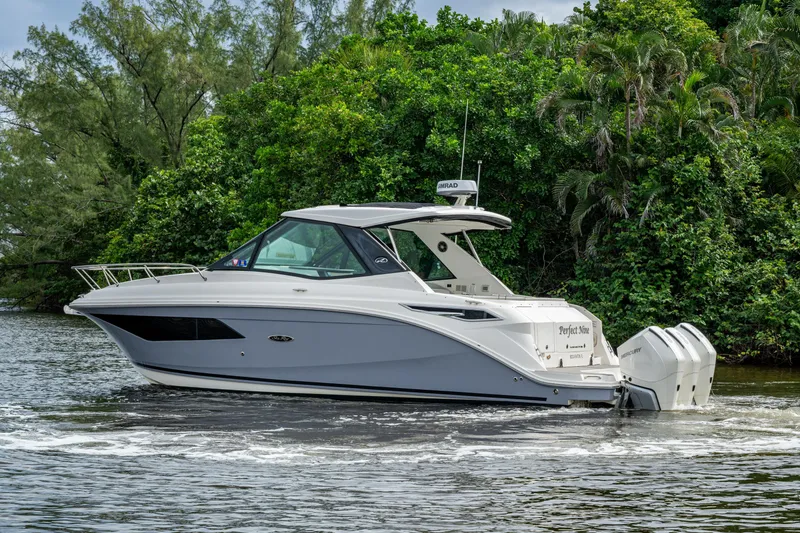 Slide: The Image of 2023 Sea Ray Sundancer 320 Outboard cruising on a scenic waterway with lush greenery. - 66