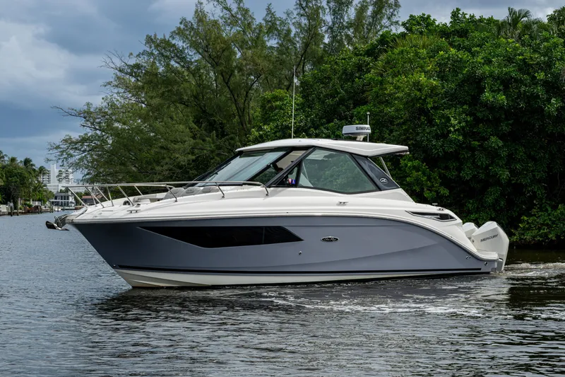 Slide: The Image of 2023 Sea Ray Sundancer 320 Outboard cruising on a serene waterway, surrounded by lush greenery. - 69