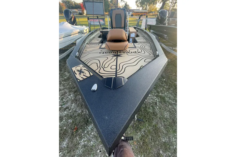 Slide: The Image of 2026 Xpress H20B Bay boat with custom deck design, parked outdoors. - 2