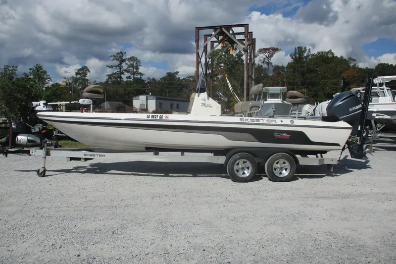 The Image of 2014 Skeeter SX240 boat on trailer, parked outdoors under cloudy sky. - 0