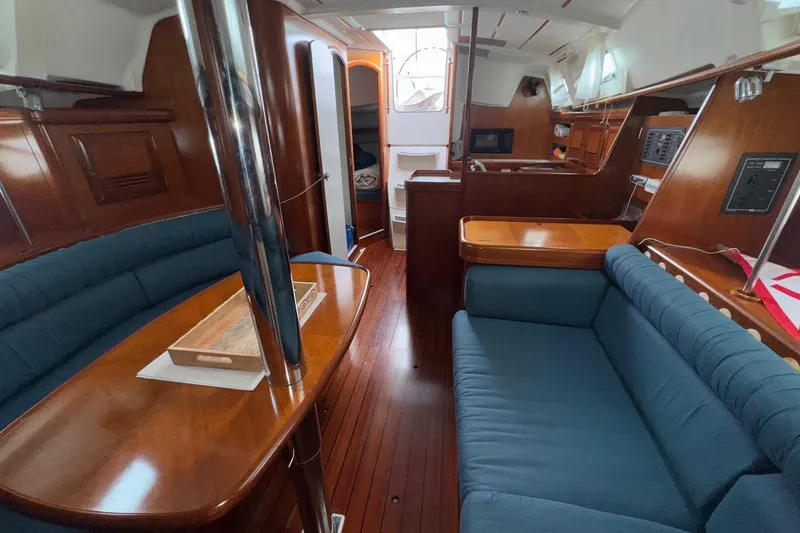 Slide: The Image of Interior of 2001 Beneteau Oceanis Clipper 361 sailboat with wooden furnishings and blue seating. - 2