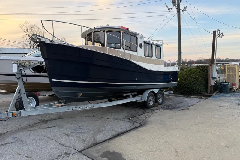 Slide: The Image of 2008 Ranger Tugs R-25 boat on trailer, parked outdoors, showcasing its classic design. - 15
