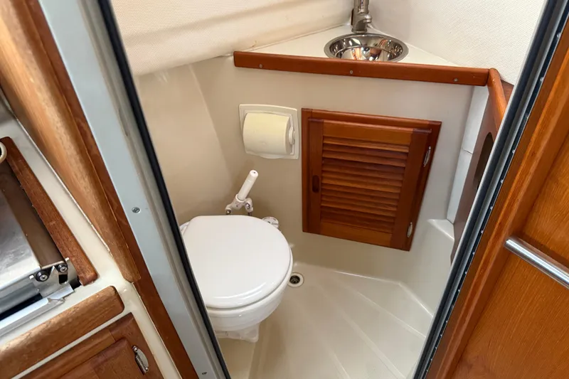 Slide: The Image of 2008 Ranger Tugs R-25 boat bathroom with toilet, sink, and wooden cabinet. - 23