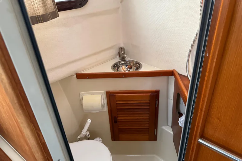 Slide: The Image of 2008 Ranger Tugs R-25 boat bathroom with sink, toilet, and wooden cabinet. - 24