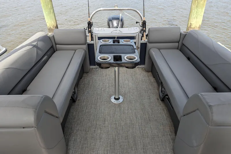 Slide: The Image of 2021 Avalon Catalina Quad Lounger interior with gray seating and table, docked on water. - 2