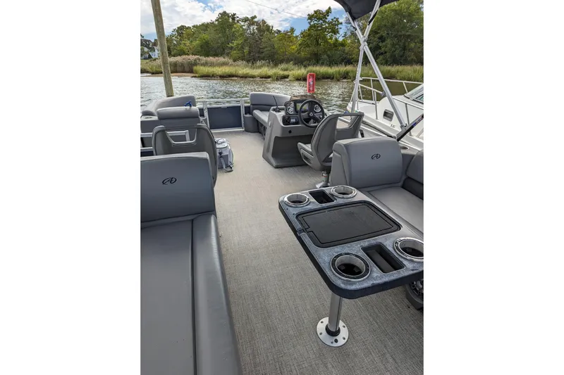 Slide: The Image of 2021 Avalon Catalina Quad Lounger boat interior with seating and table on a calm river. - 3