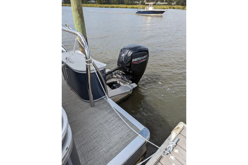 Slide: The Image of 2021 Avalon Catalina Quad Lounger boat interior with fishing rods at sunset. - 7