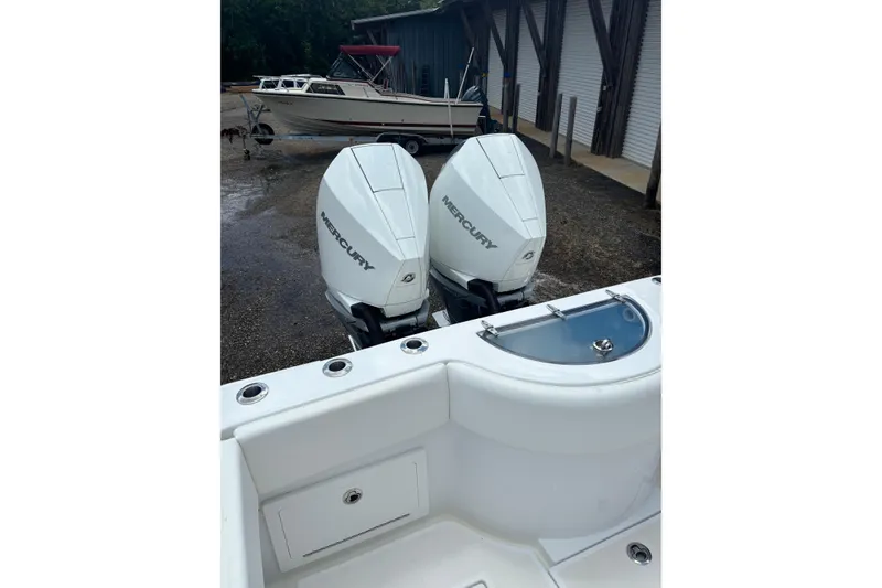 Slide: The Image of 2022 Onslow Bay 27 boat with twin Mercury outboard engines, docked near a storage facility. - 5
