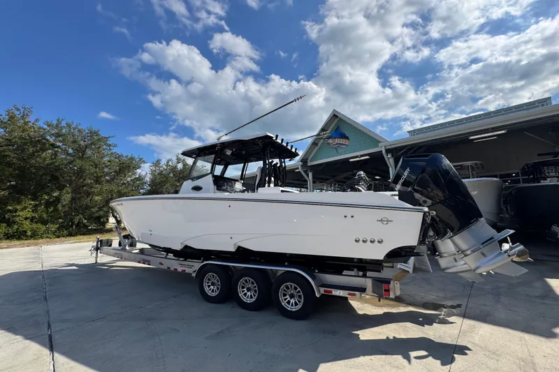 Slide: The Image of 2025 Fountain 32 NX boat on trailer under blue sky, parked outdoors. - 14