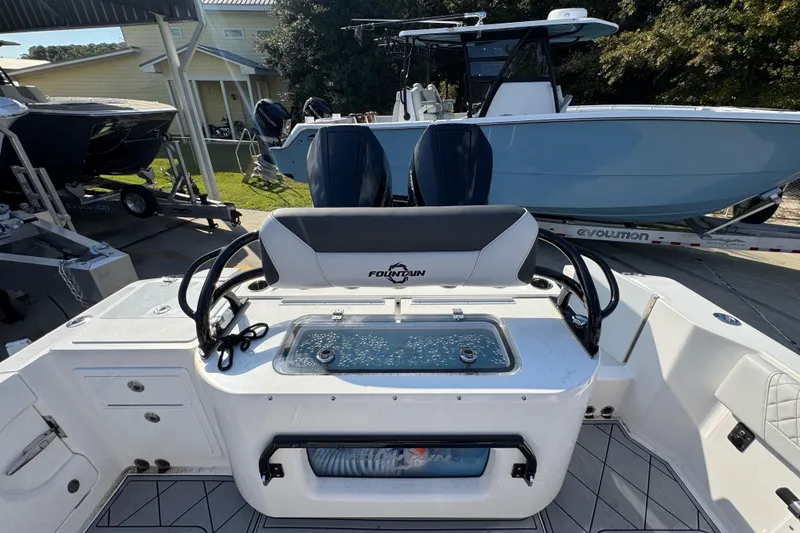 Slide: The Image of 2025 Fountain 32 NX boat interior with seating and control panel, parked outdoors. - 34