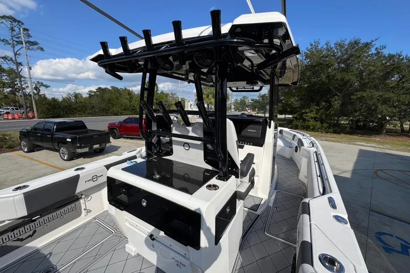 Slide: The Image of 2025 Fountain 32 NX boat interior with modern helm and seating, parked outdoors. - 36