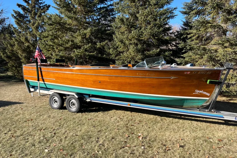 The Image of 1938 Chris-Craft 28 Sportsman wooden boat on trailer, surrounded by trees. - 1