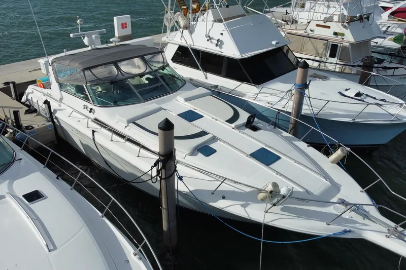 The Image of 1990 Sea Ray 420 Sundancer yacht docked at marina, surrounded by other boats. - 1