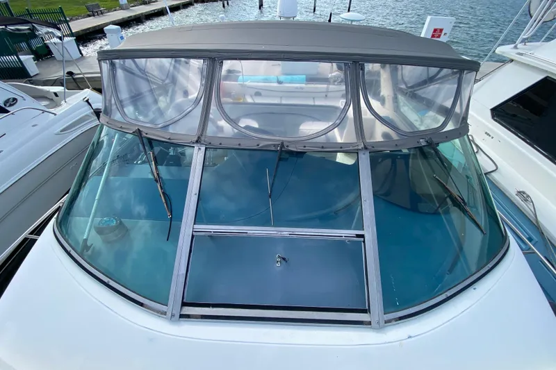 Slide: The Image of 1990 Sea Ray 420 Sundancer boat with clear canopy and windshield, docked at marina. - 23