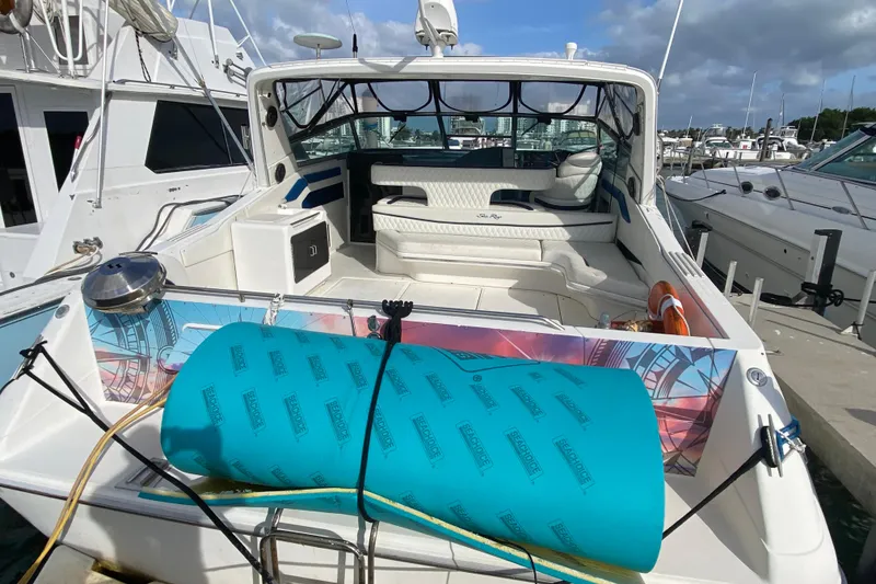 Slide: The Image of 1990 Sea Ray 420 Sundancer yacht docked, featuring spacious seating and vibrant deck accessories. - 24