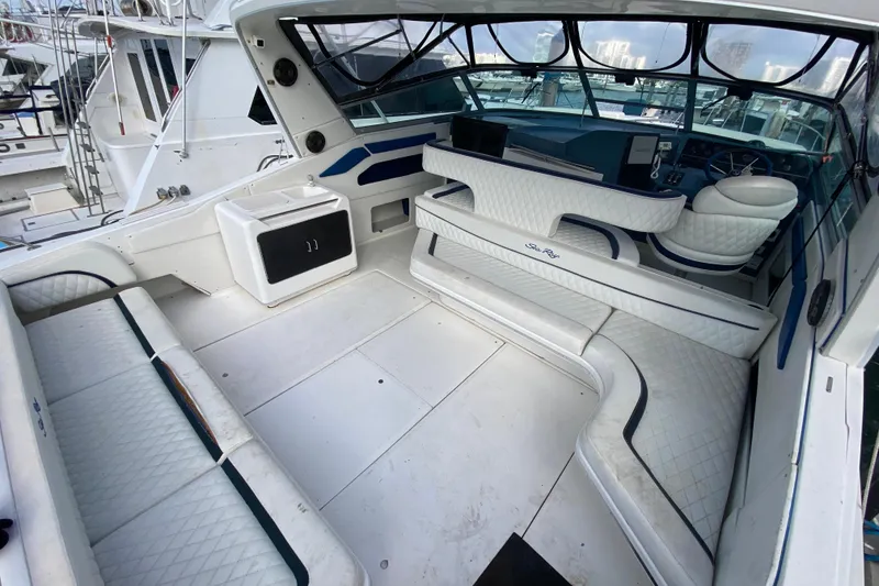 Slide: The Image of 1990 Sea Ray 420 Sundancer interior with white seating and helm, docked at marina. - 25