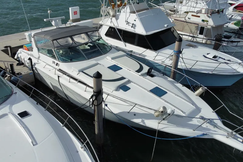 Slide: The Image of 1990 Sea Ray 420 Sundancer yacht docked at marina, surrounded by other boats. - 6