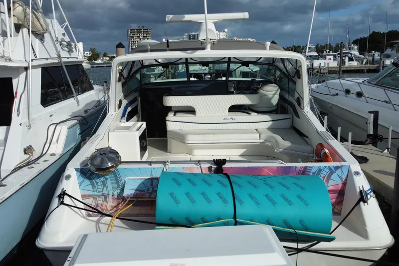 Slide: The Image of 1990 Sea Ray 420 Sundancer yacht docked at marina, featuring spacious seating and vibrant accessories. - 61
