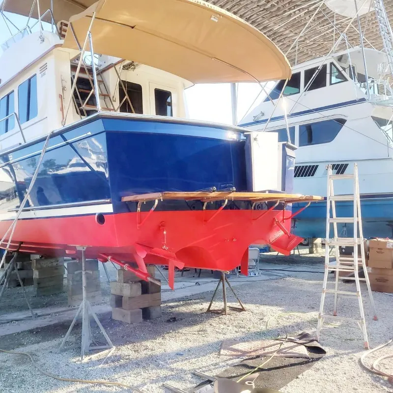 Slide: The Image of 2004 Sabre 36 Flybridge Fast Trawler in dry dock, blue and red hull, under maintenance. - 2