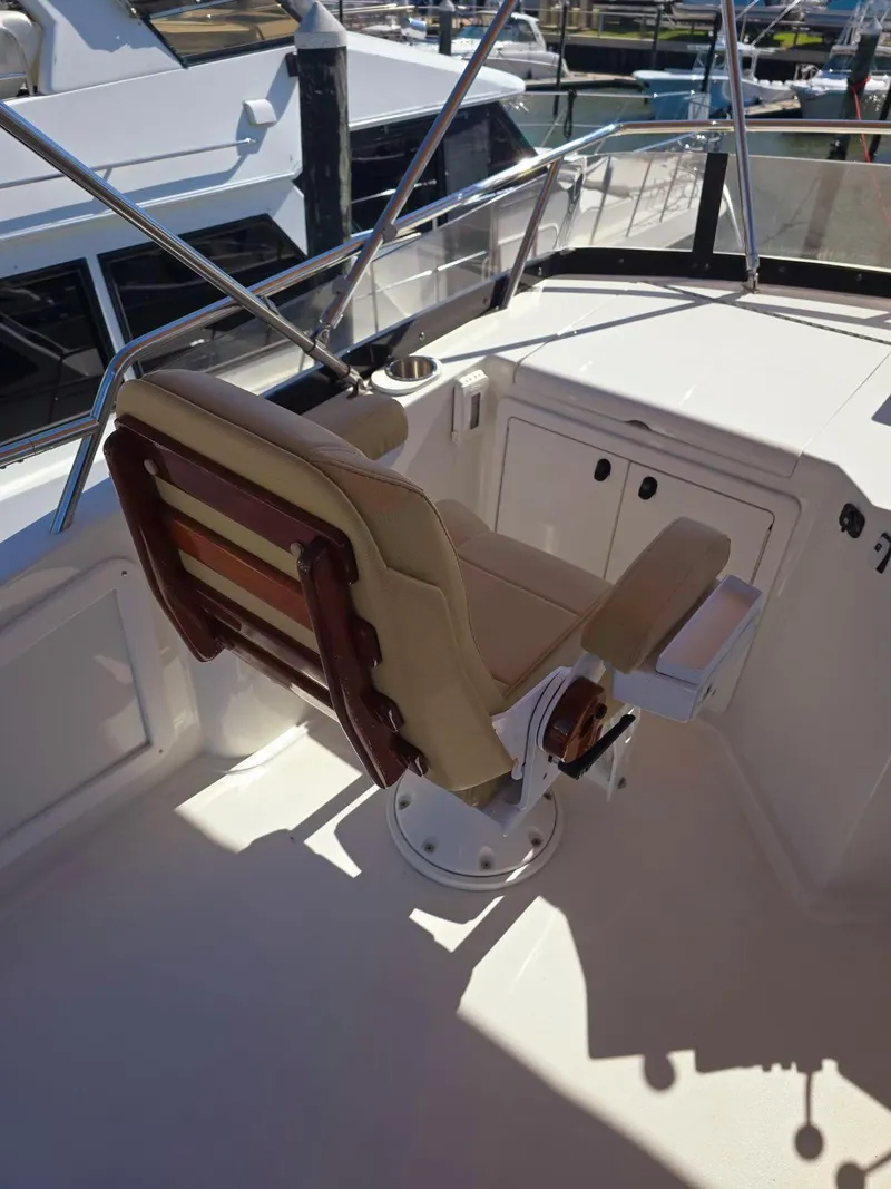 Slide: The Image of 2004 Sabre 36 Flybridge Fast Trawler helm seat with wooden accents and marina view. - 38