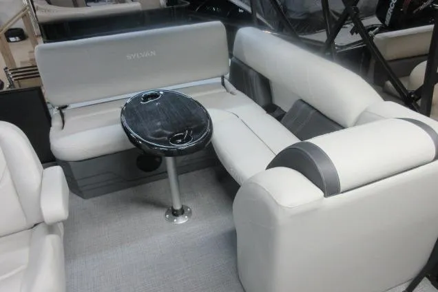Slide: The Image of 2026 Sylvan Mirage 822 CLZ boat interior with plush seating and a sleek table. - 6